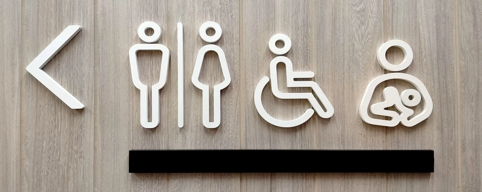 Witte sanitaire pictogrammen op een licht houten wand
